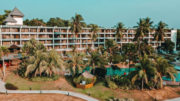 A hotel with multiple floors, a pool area, and palm trees. - Tunamaya Beach & Spa Resort – Desaru (Bandar Penawar)