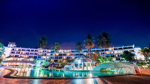 A hotel with a swimming pool, palm trees, and a night sky. - Tunamaya Beach & Spa Resort – Desaru (Bandar Penawar)
