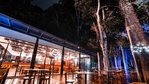 An outdoor dining area with wooden tables and chairs, surrounded by trees. - Tunamaya Beach & Spa Resort – Desaru (Bandar Penawar)