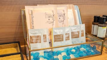 A display of skincare products including Moisture Rich Lotion, Vitalizing Cream, and Cleansing Cream, along with a glass container filled with blue and white stones.