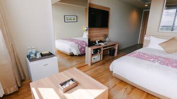 A hotel room with two beds, a desk, a coffee machine, and a TV.