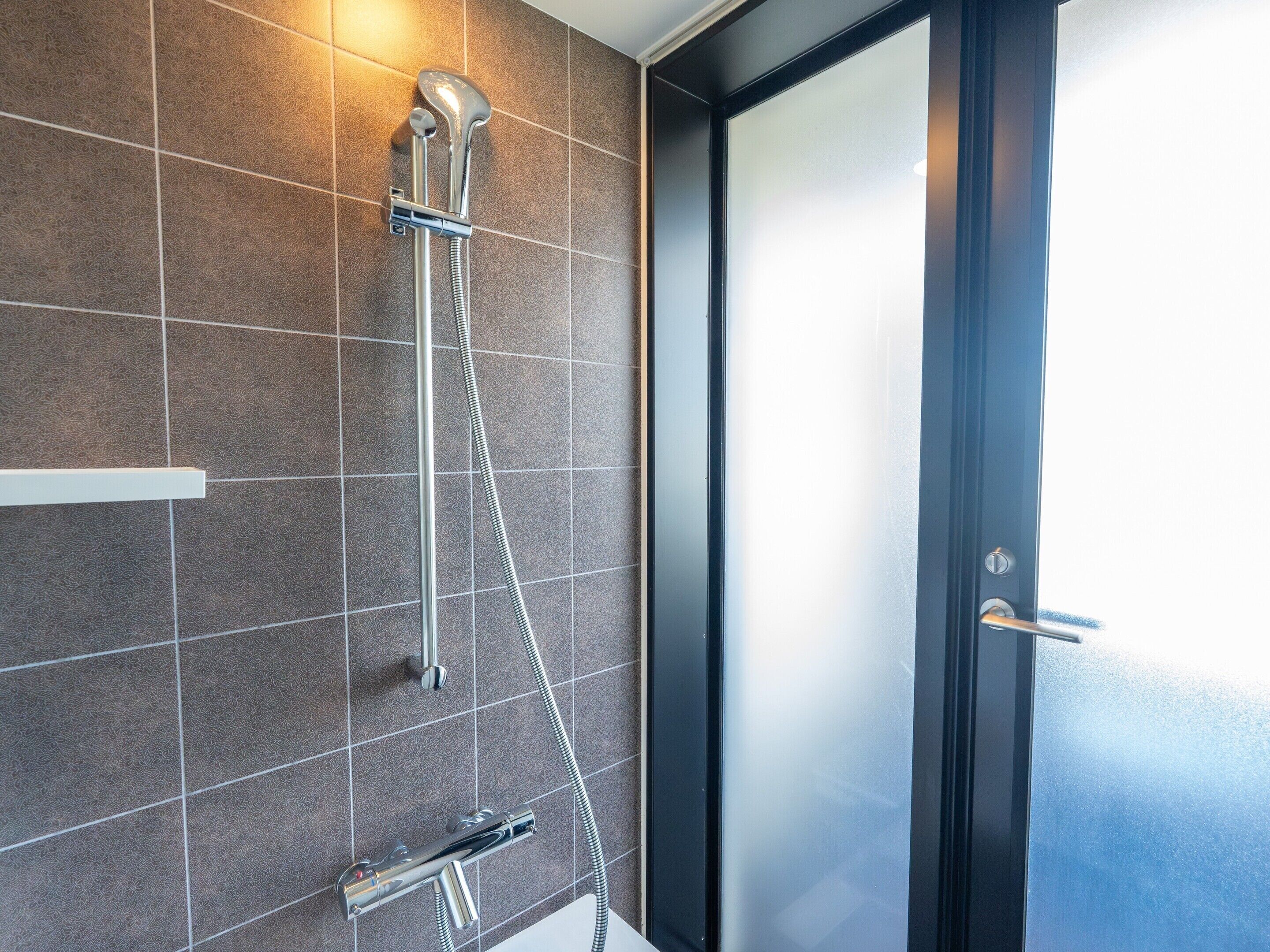 A modern bathroom with a shower, tiled walls, and a door.