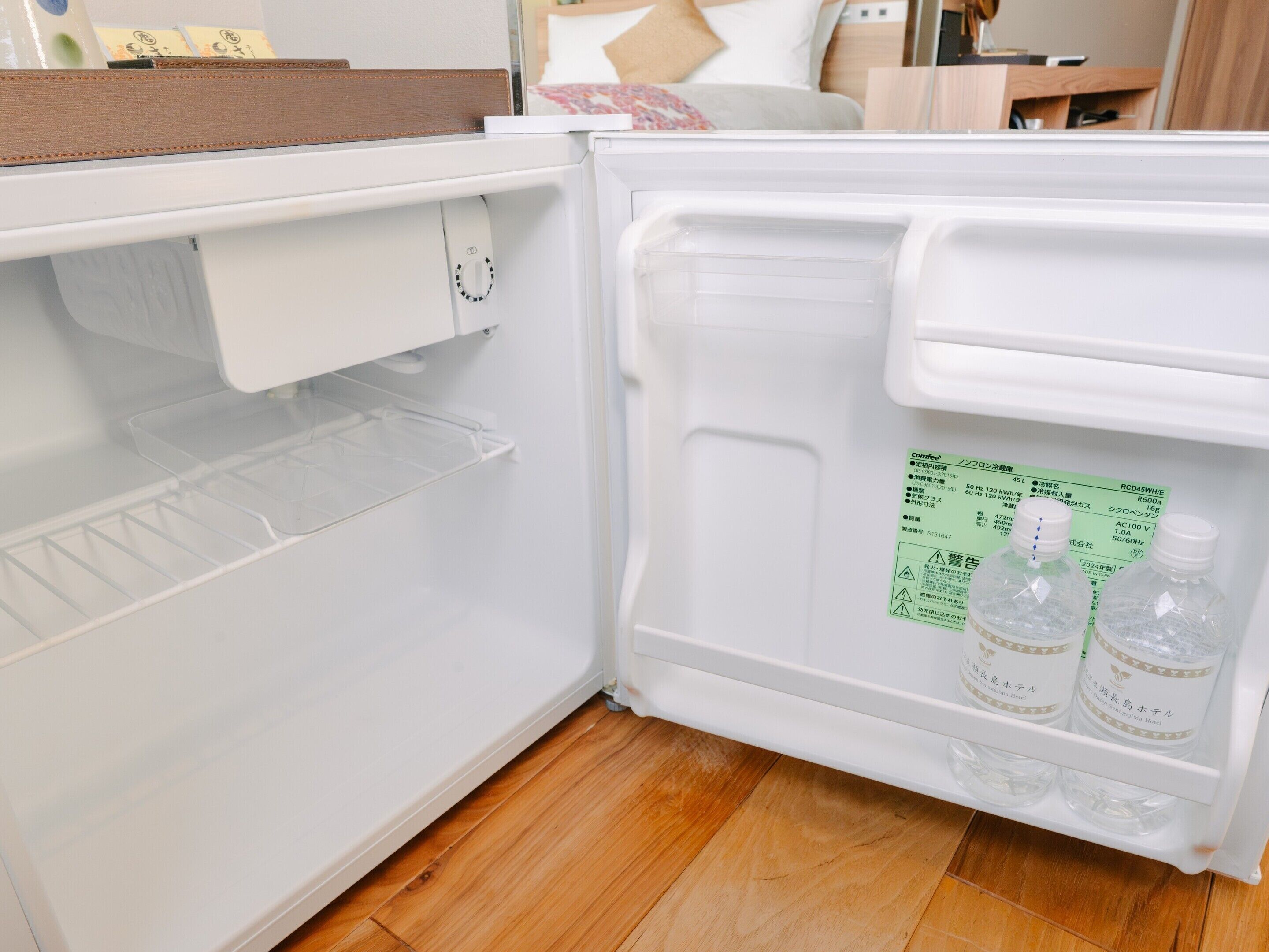 A clean, empty refrigerator with a built-in wine cooler and a shelf with two bottles of water.
