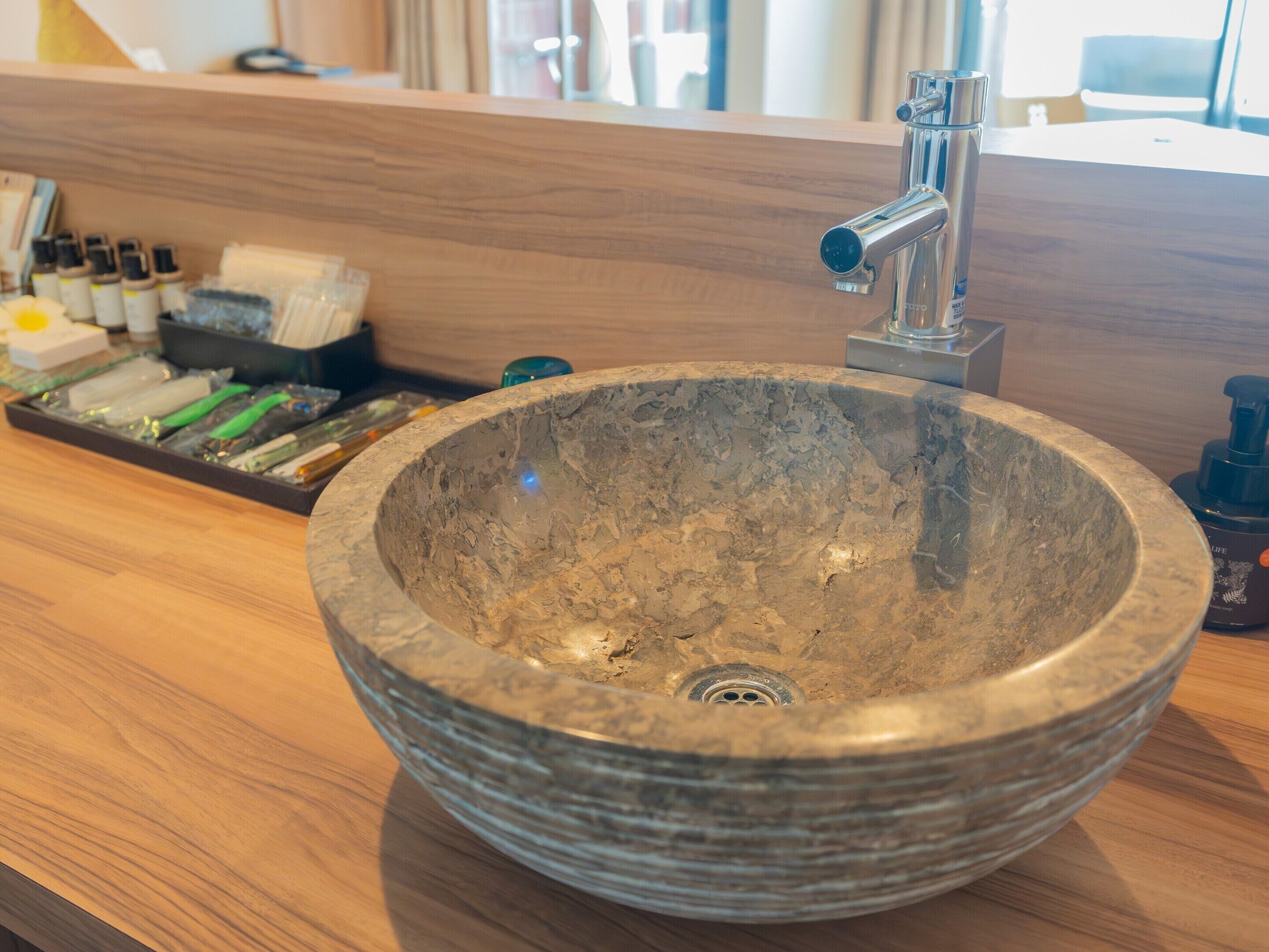 A stone sink with a modern faucet in a hotel bathroom.