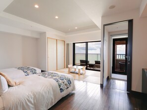 Una habitación de hotel con una cama grande, un balcón con mesa y sillas, y vistas al mar.