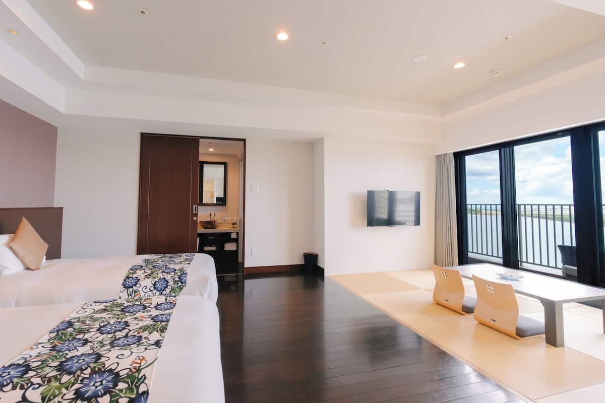 A hotel room with a large bed, a desk, and a view of the sky.