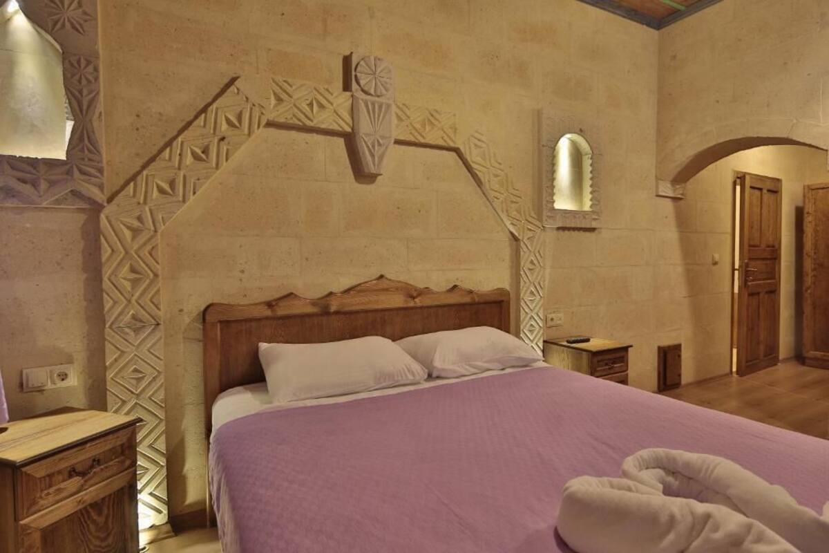 A bedroom with a wooden bed, a purple bedspread, and a decorative wall arch.