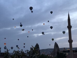 Vista de un paisaje urbano histórico con un alminar destacado y varios globos aerostáticos en el cielo.