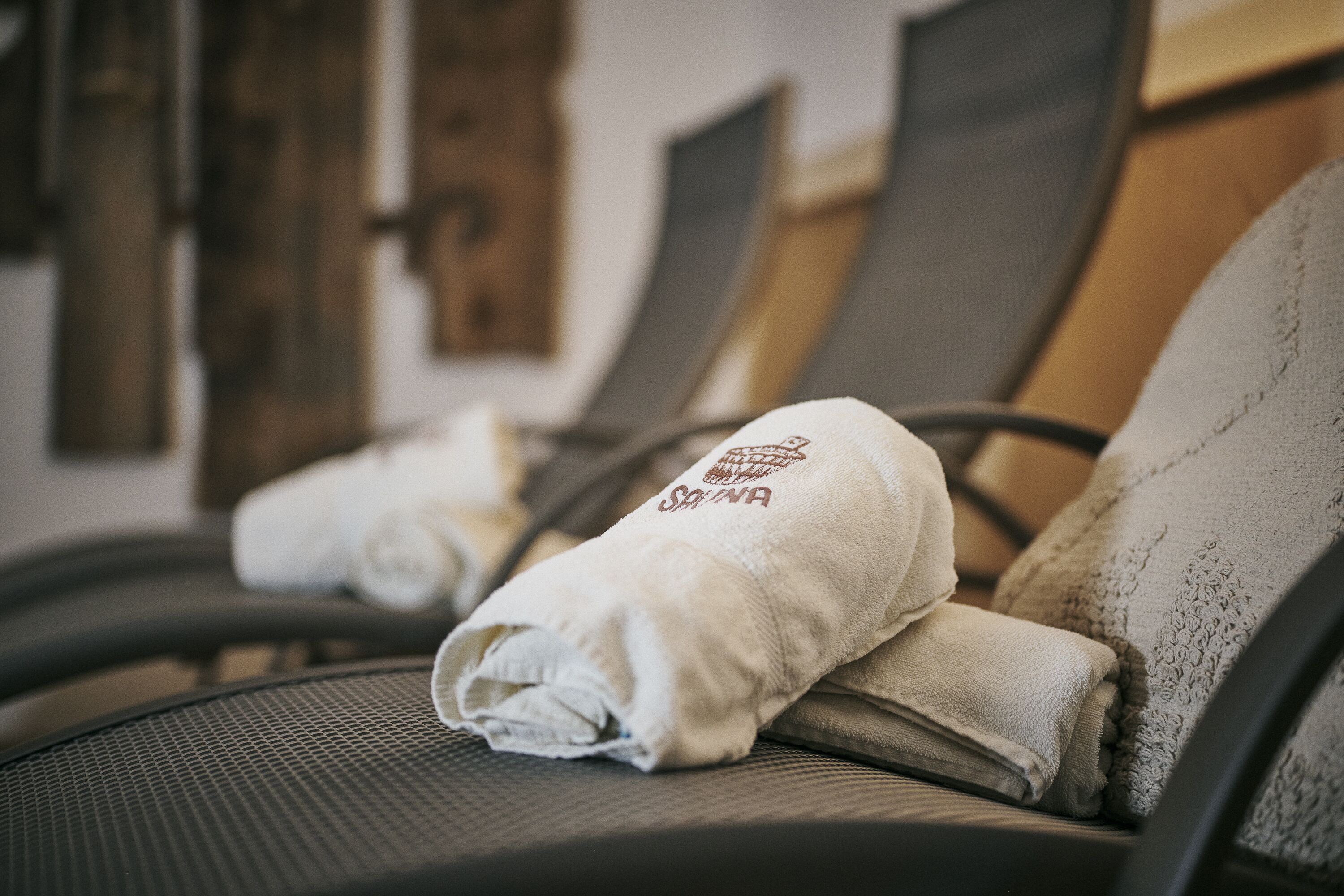 Eine Reihe von Massagesesseln mit daraufgelegten Handtüchern, was auf einen Spa- oder Entspannungsbereich hindeutet.