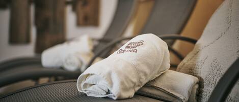 Eine Reihe von Massagesesseln mit daraufgelegten Handtüchern, was auf einen Spa- oder Entspannungsbereich hindeutet.