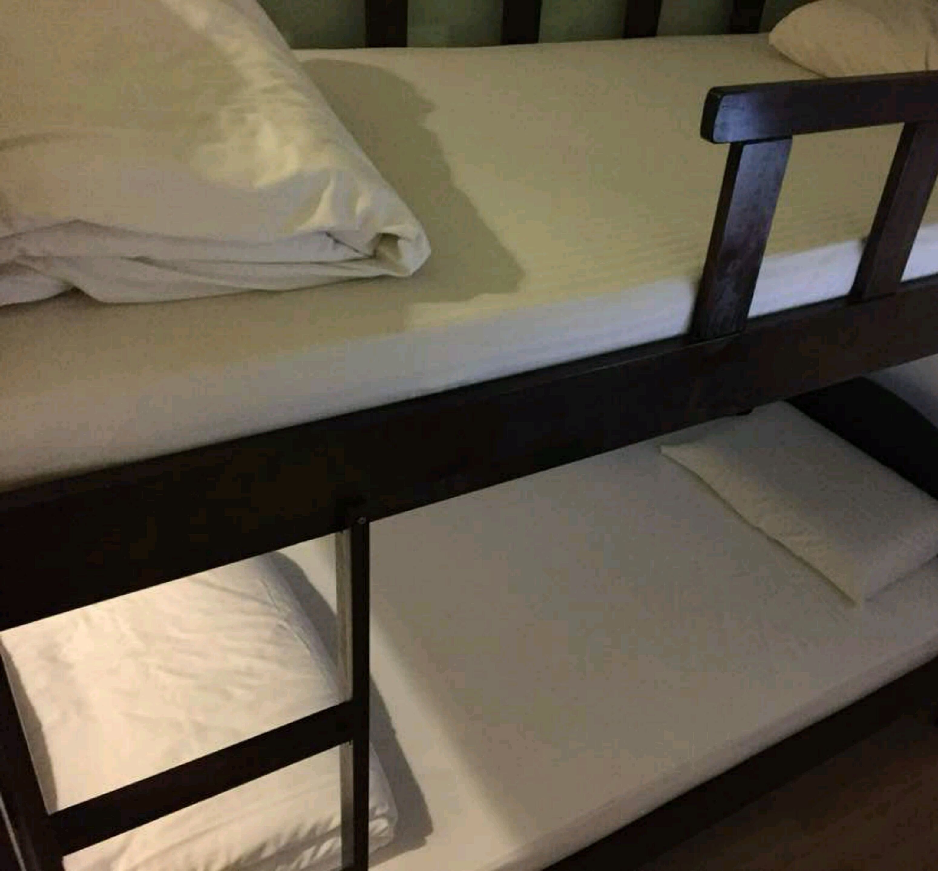 A bunk bed with white bedding and a wooden frame.