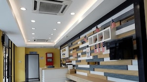 Zona de recepción con diseño moderno, que destaca por una paleta de colores blanco y madera, un televisor de pantalla plana y banderas estadounidenses.