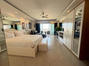 A modern bedroom with a large bed, a desk, and a wardrobe. - View Talay 6 Condominium by Honey (Pattaya)