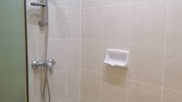 A shower area with a handheld showerhead, a wall-mounted faucet, and a soap dish.