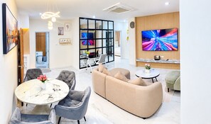 A modern living room with a sofa, chairs, a coffee table, and a TV. - View Talay 6 Condominium by Honey (Pattaya)