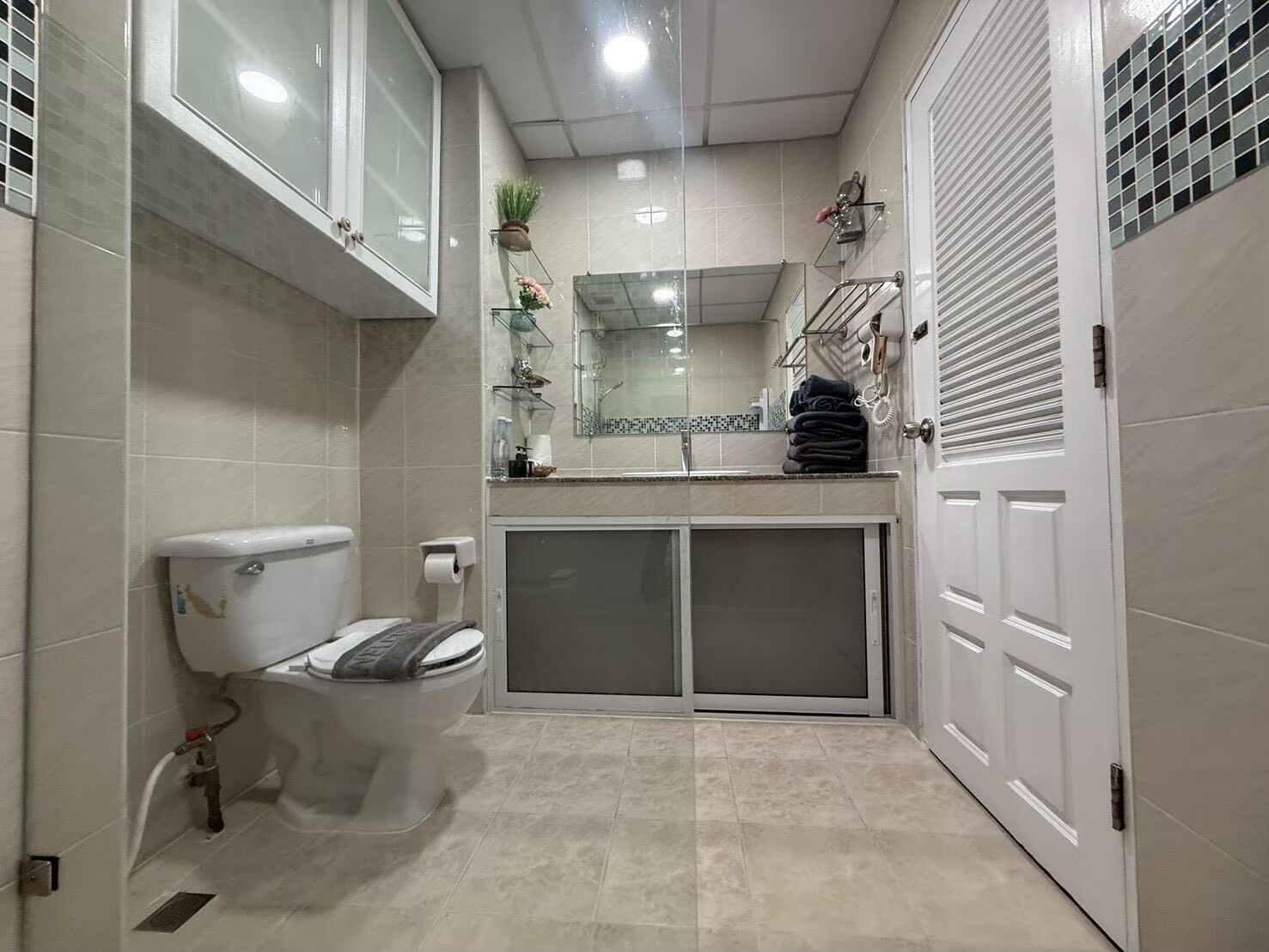 A bathroom with a toilet, a sink, a mirror, and a shower area.