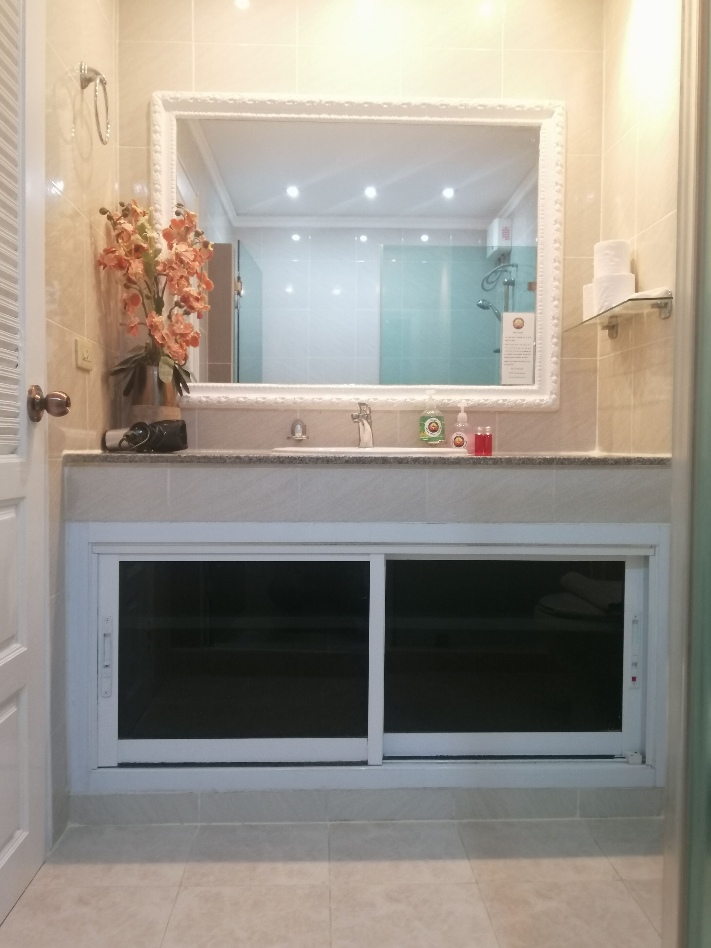 Une salle de bain avec un grand miroir, un lavabo avec un porte-serviettes et des toilettes.
