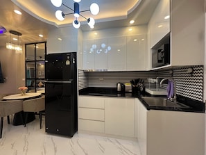 Una cocina moderna con un refrigerador negro, gabinetes blancos y un salpicadero con estampado blanco y negro.