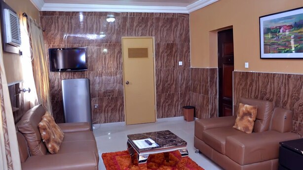 Una sala de estar moderna con un sofá de cuero marrón, una mesita de centro, un televisor de pantalla plana montado en la pared y una puerta con rejilla.