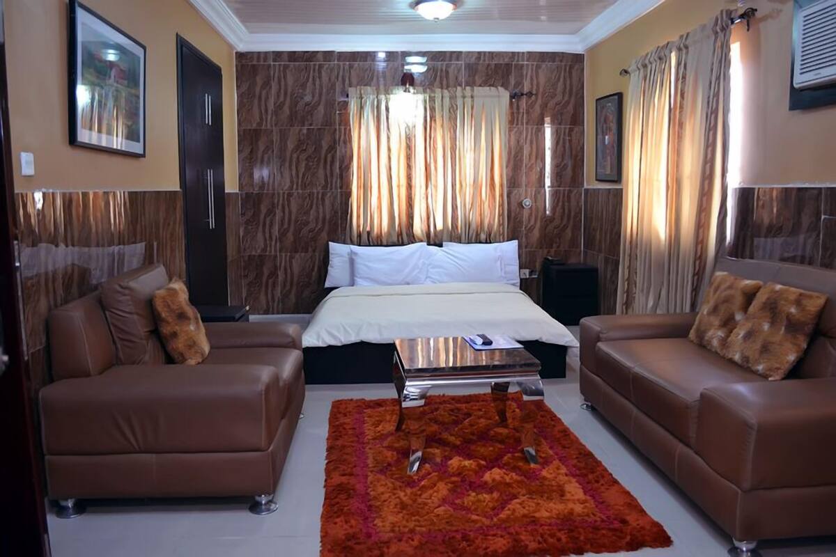 A hotel room with a bed, two sofas, a coffee table, and a patterned rug.