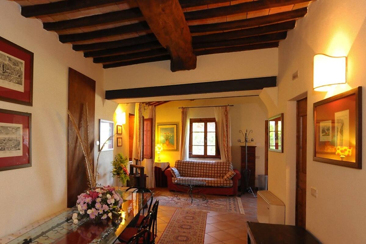 A hallway with framed historical photographs, a dining area with a table and chairs, and a sofa in the background.