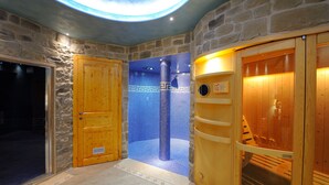 A stone-walled room with a wooden door, a blue-tiled shower area, and a wooden sauna. - Borgo Mandoleto (Perugia)