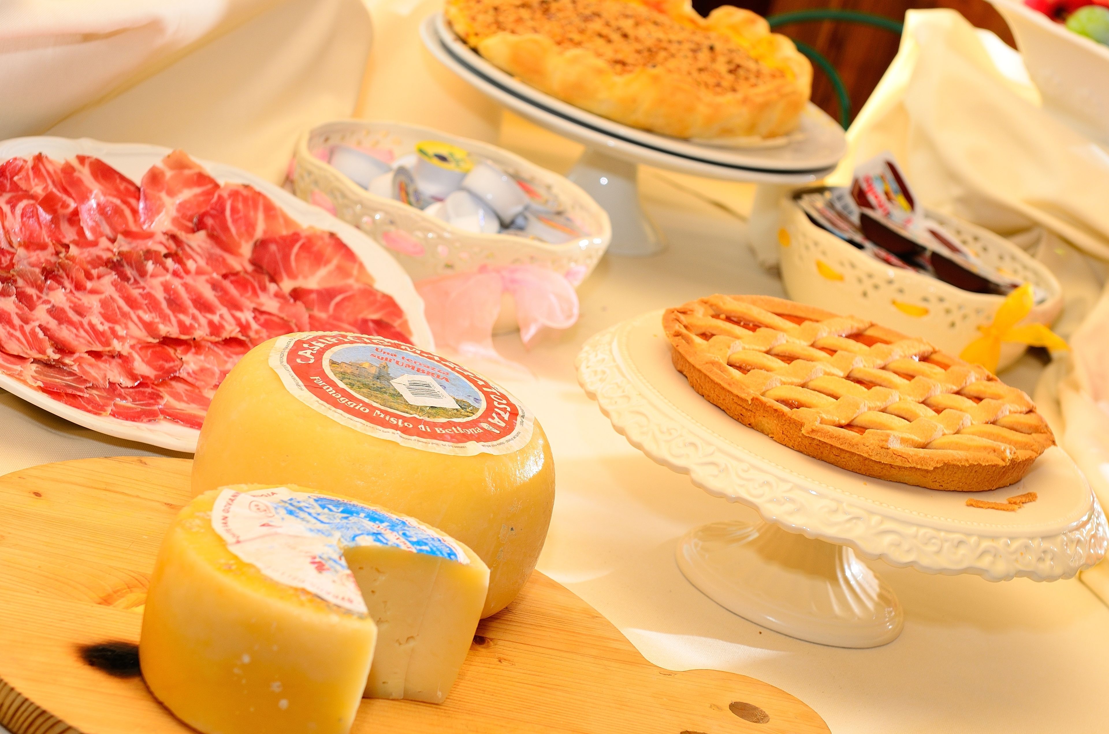 A cheese board with various types of cheese and a pie on a table.