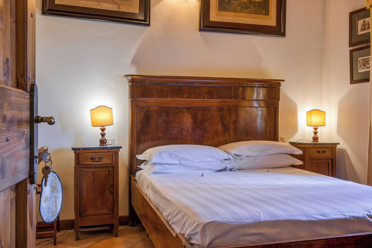 A neatly made bed with white linens, two bedside tables with lamps, and a wooden headboard.