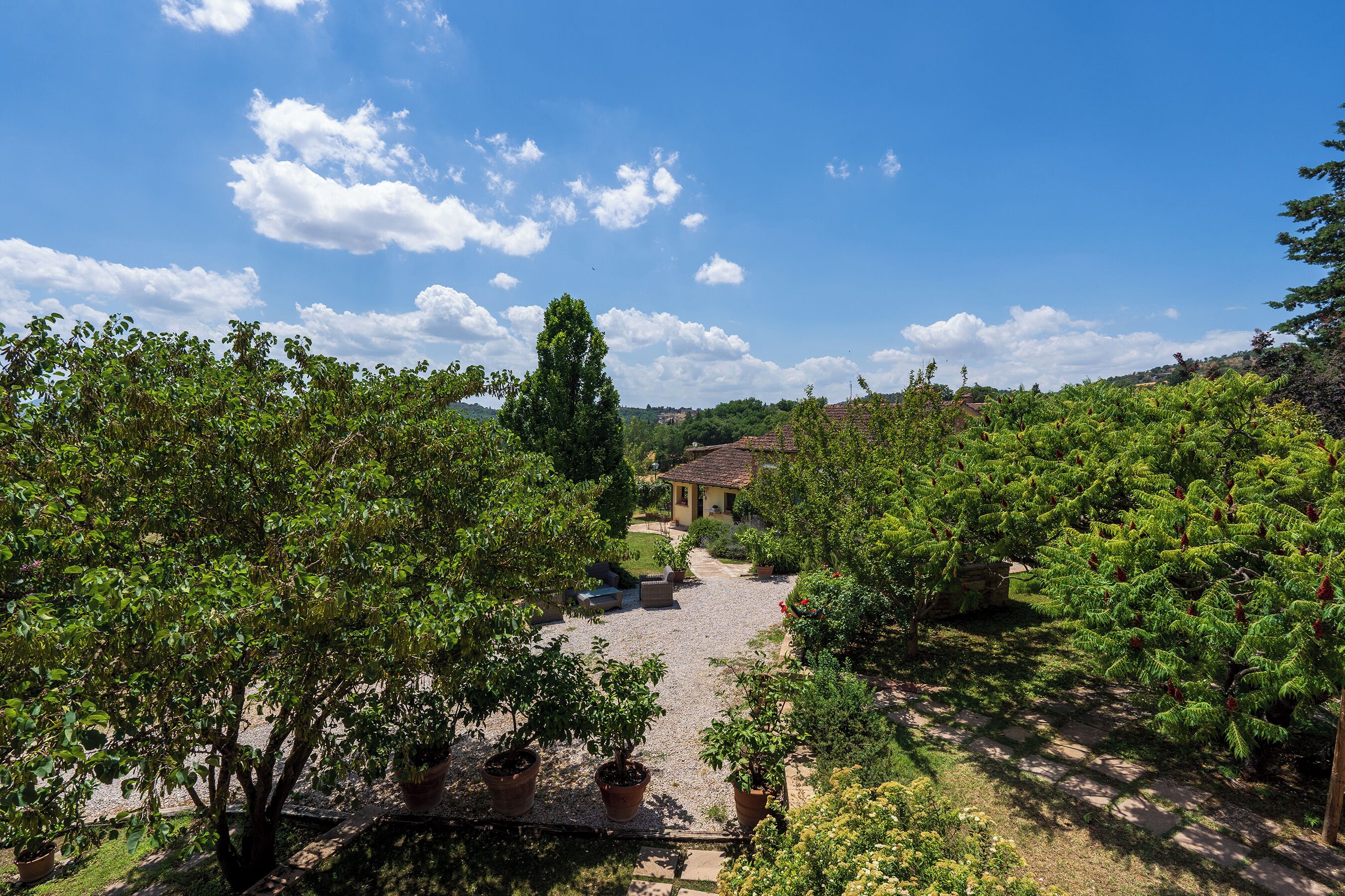 Ein Innenhof mit Kiesweg, Topfpflanzen und einem Gebäude im Hintergrund.