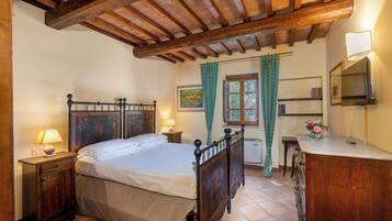 A bedroom with a wooden bed, bedside tables, a dresser, a mirror, and a window with curtains.