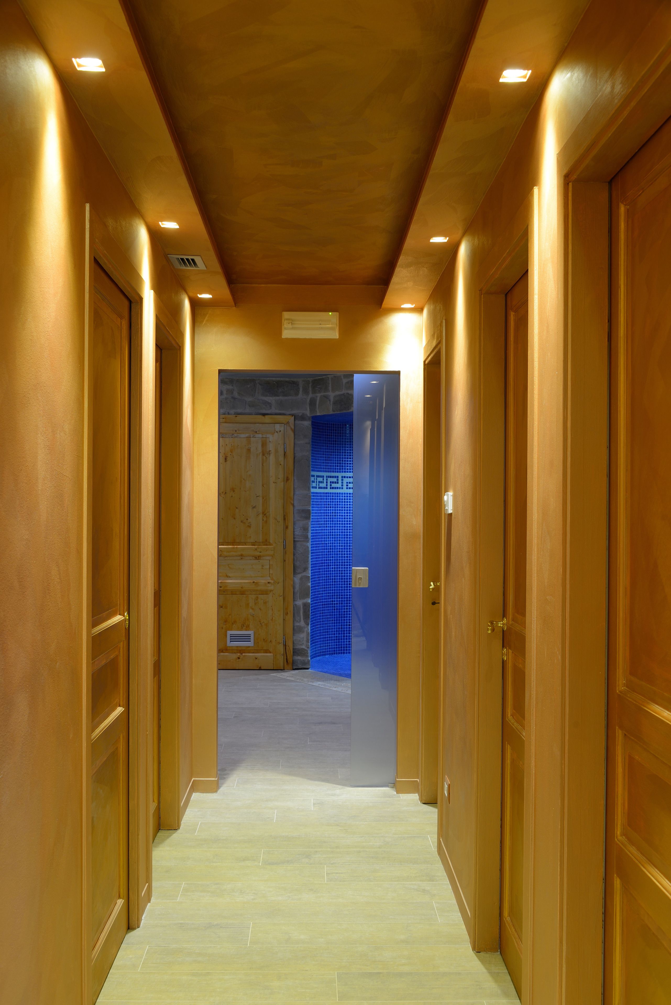 A hallway with wooden doors and a blue tiled wall at the end.