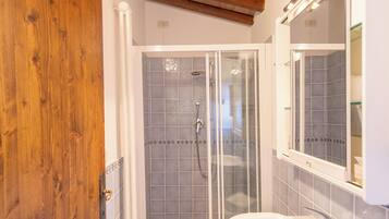 A bathroom with a wooden door, a glass shower enclosure, and a white sink.