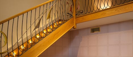 Una habitación acogedora con una escalera de madera, un escritorio con una computadora, una silla y una cafetera.