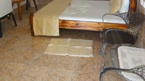 Une chambre d’hôtel avec un lit, une chaise, une petite table et un miroir.