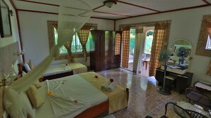 Une chambre avec deux lits, un bureau, une chaise, un ventilateur et une fenêtre avec des rideaux.