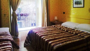 Een hotelkamer met twee bedden, een groot raam met gordijnen, een nachtkastje met een lamp, en een lijst met een afbeelding aan de muur.