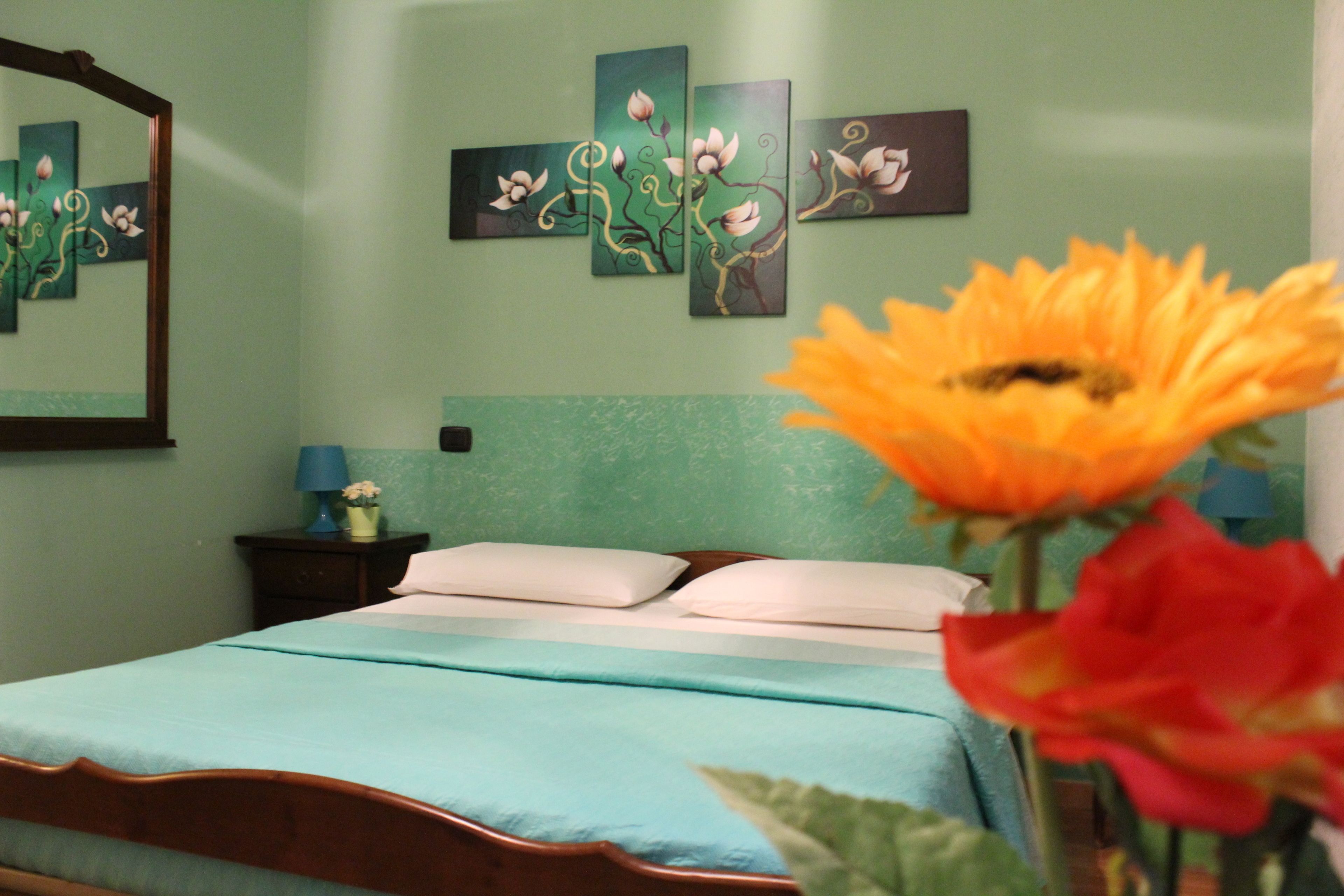 A bedroom with a bed, pillows, a nightstand, a lamp, and wall art.