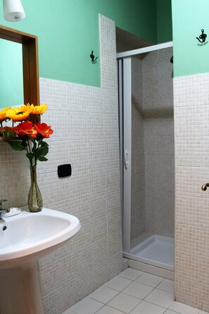 Un baño con lavamanos, ducha y espejo.