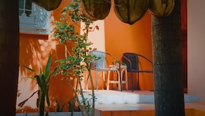 An outdoor seating area with a table and chairs, surrounded by potted plants and a palm tree. - Sarin Guesthouse (Koh Tao)