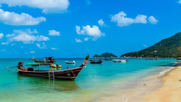 A beach with clear turquoise waters, boats, and a sandy shore. - Sarin Guesthouse (Koh Tao)
