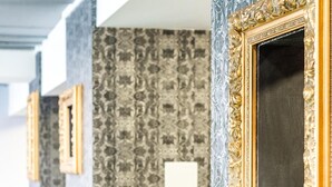 Una habitación con papel tapiz estampado, un sofá verde y cuadros en la pared.