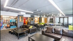 Un área de descanso moderna con asientos, una mesa de centro y una pared decorada con carteles.
