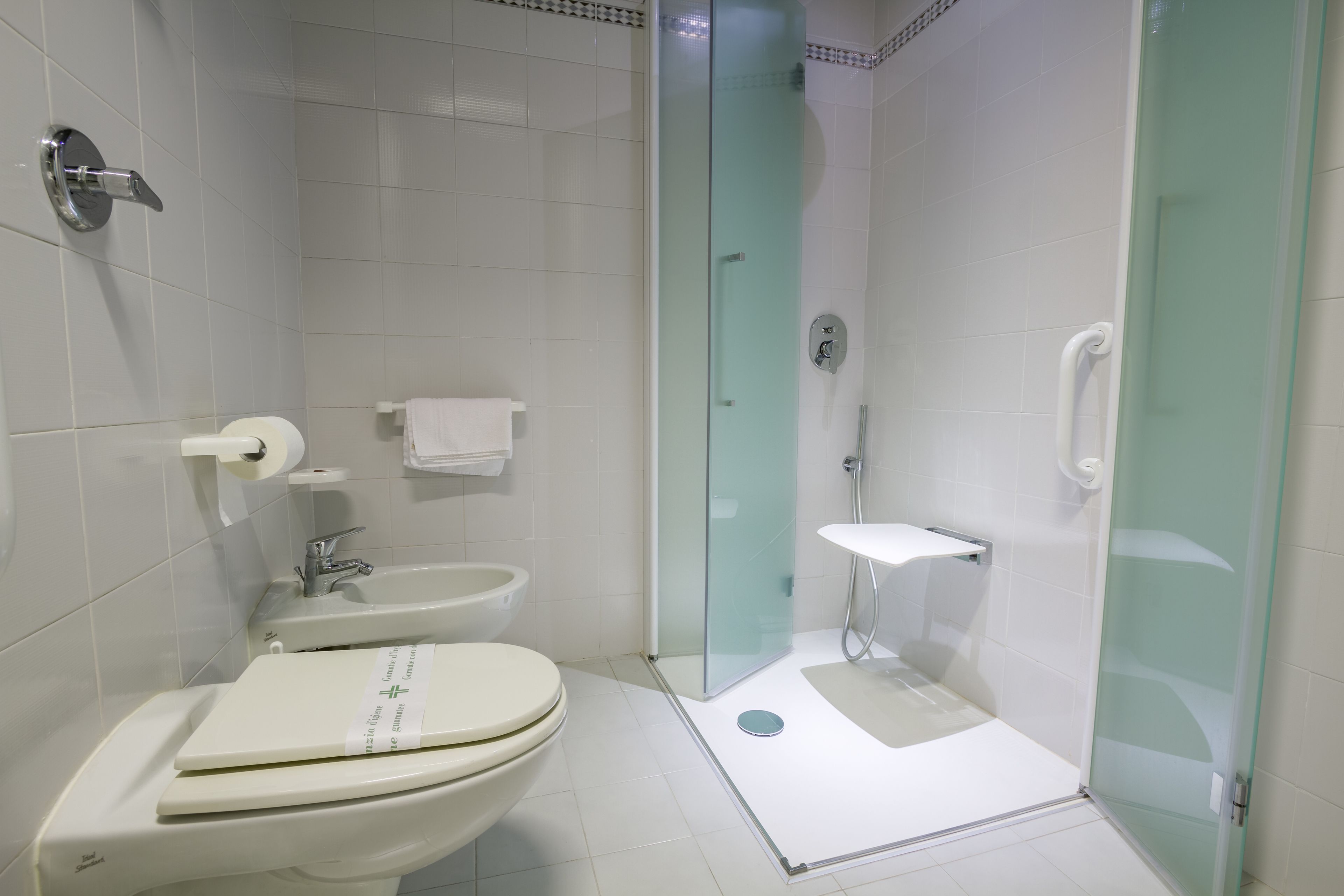 A modern bathroom with a toilet, bidet, and glass-enclosed shower area.