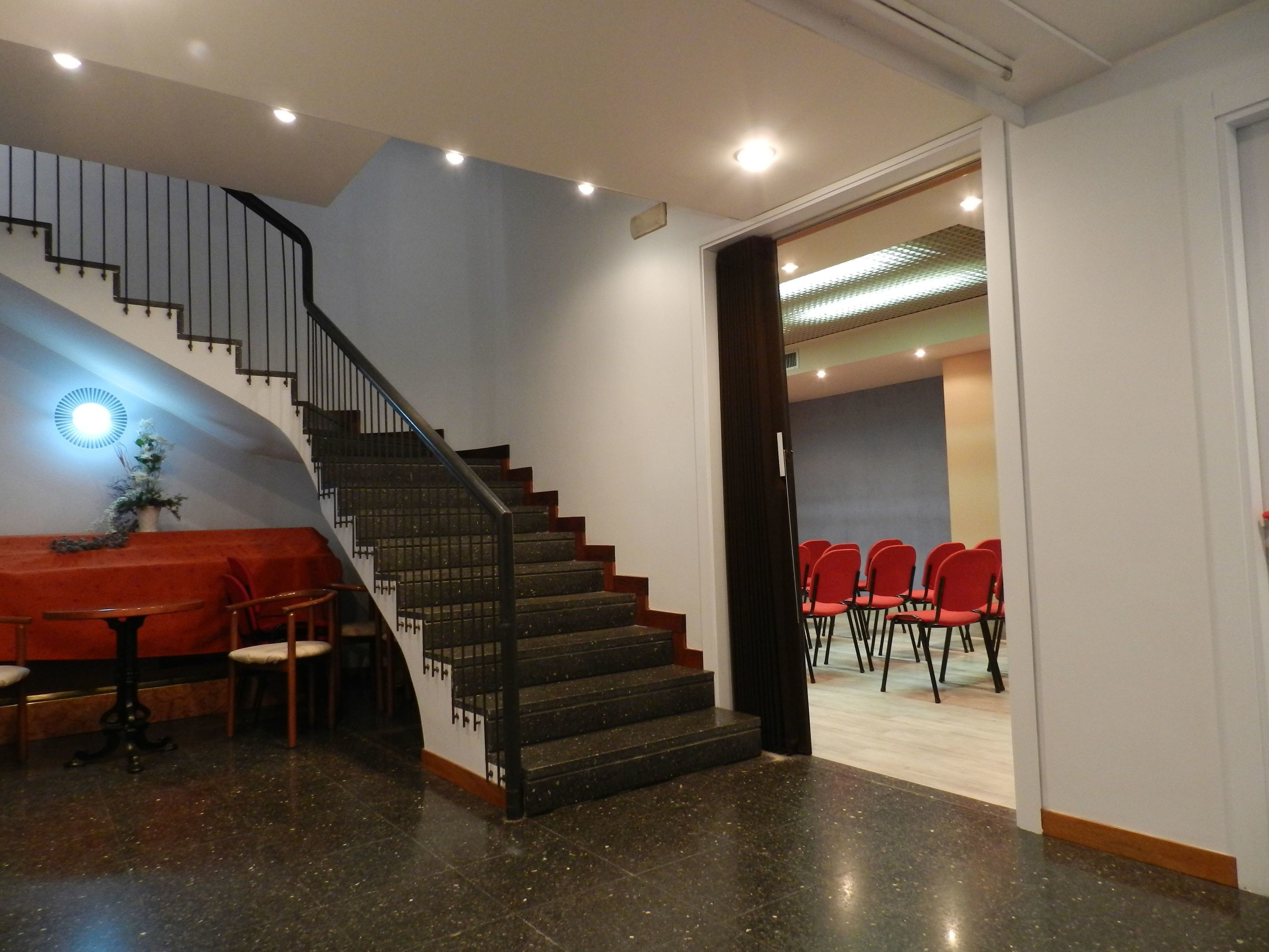 Una escalera que conduce a una habitación con un sofá rojo, una mesita y una planta en maceta.