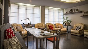 A modern living room with a sofa, armchairs, a coffee table, and a dining table. - Hotel Italia (Stradella)