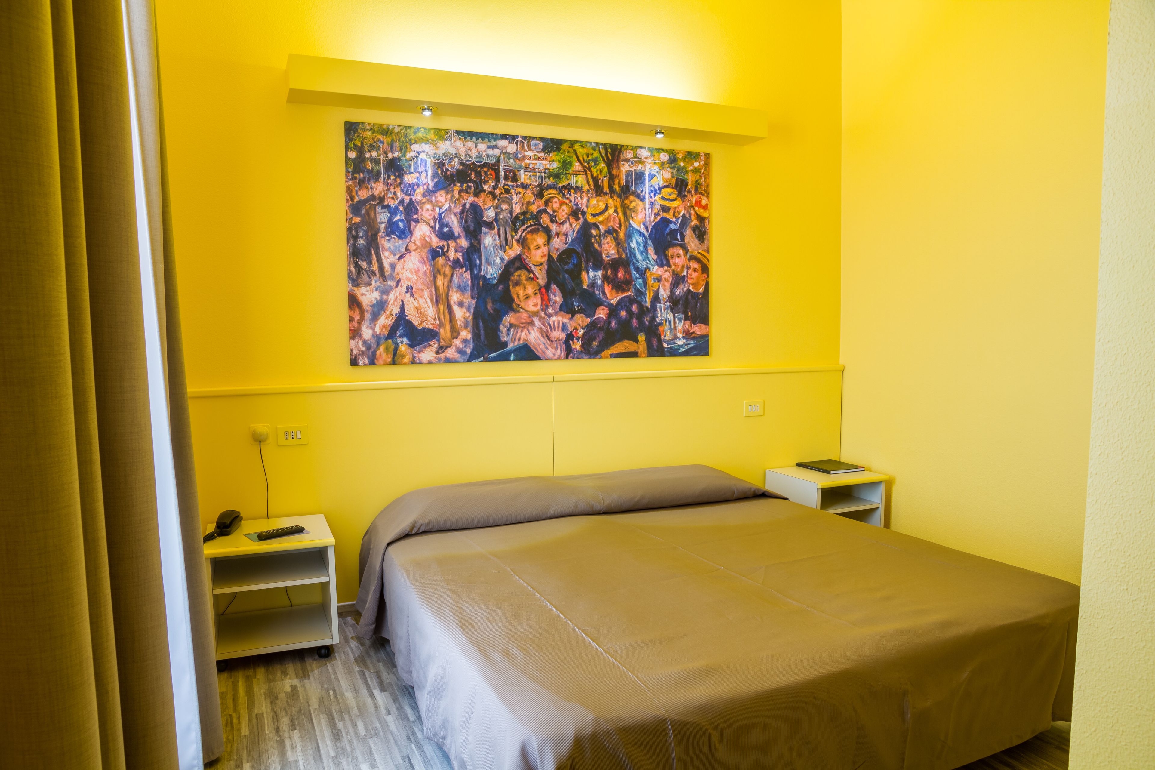 A bedroom with a bed, a nightstand, a bedside table, and a painting on the wall.