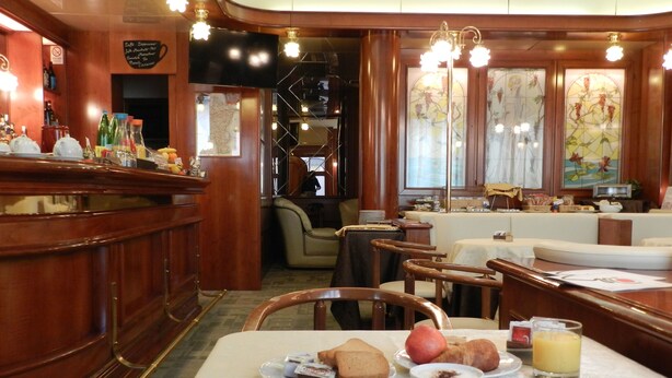 A dining area with wooden furniture, a bar, and a television. - Hotel Italia (Stradella)