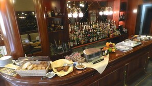 A bar area with a variety of liquor bottles, a coffee machine, and food items like croissants and pastries. - Hotel Italia (Stradella)