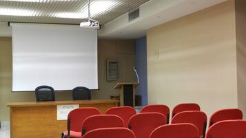 A conference room with a podium, a whiteboard, and red chairs.