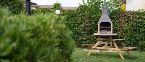 Un jardin avec un four à pizza au bois, une table de pique-nique et un lampadaire.